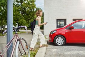 Frau läuft mit ihrem Handy zum stadtmobil-Fahrzeug